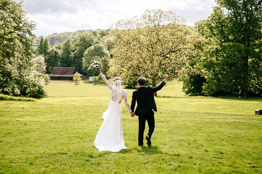 happy bride and groom walk towards dyers barn